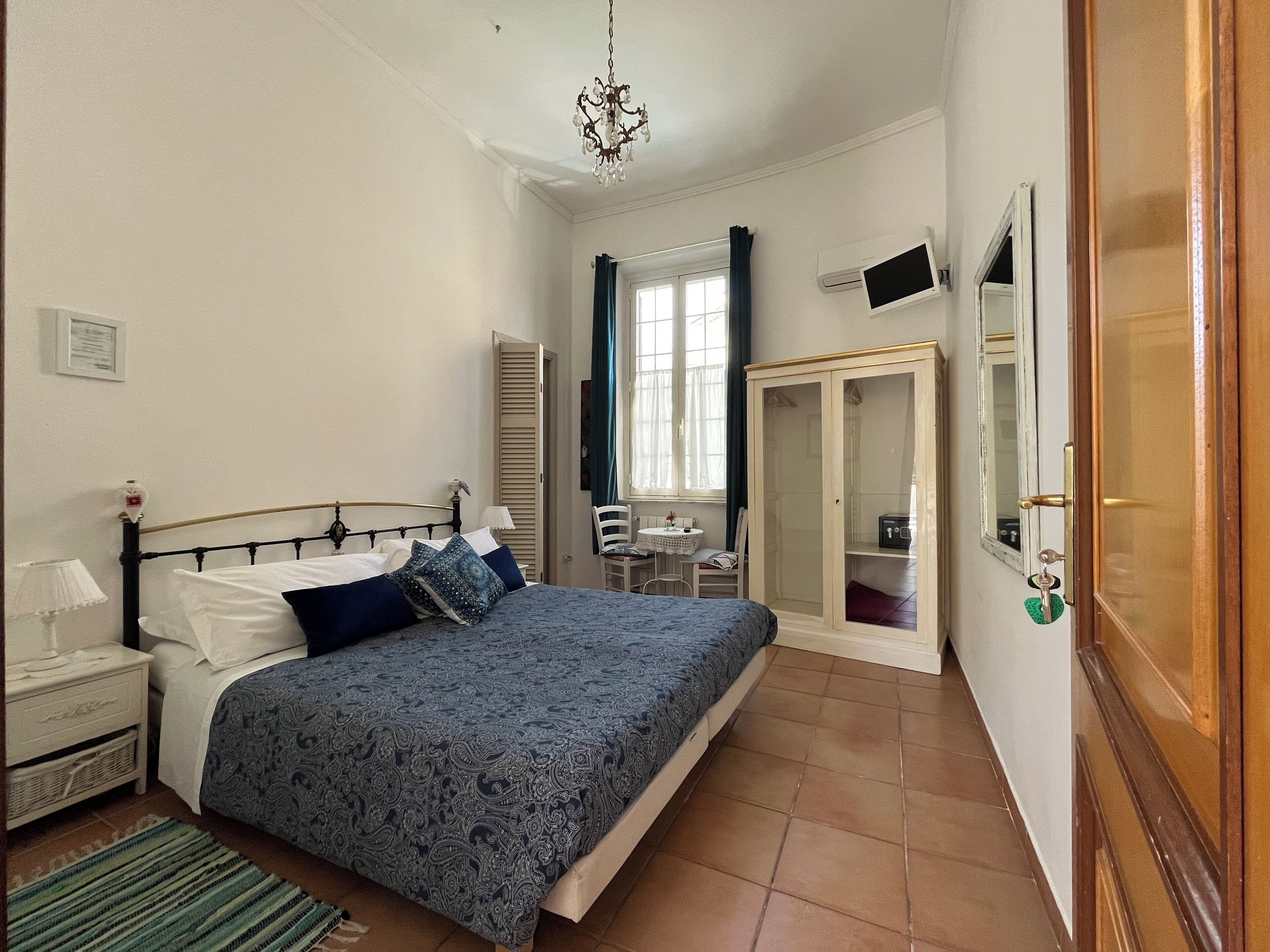 Un dormitorio con cama, mesita de noche, lámpara, ventana y armario.