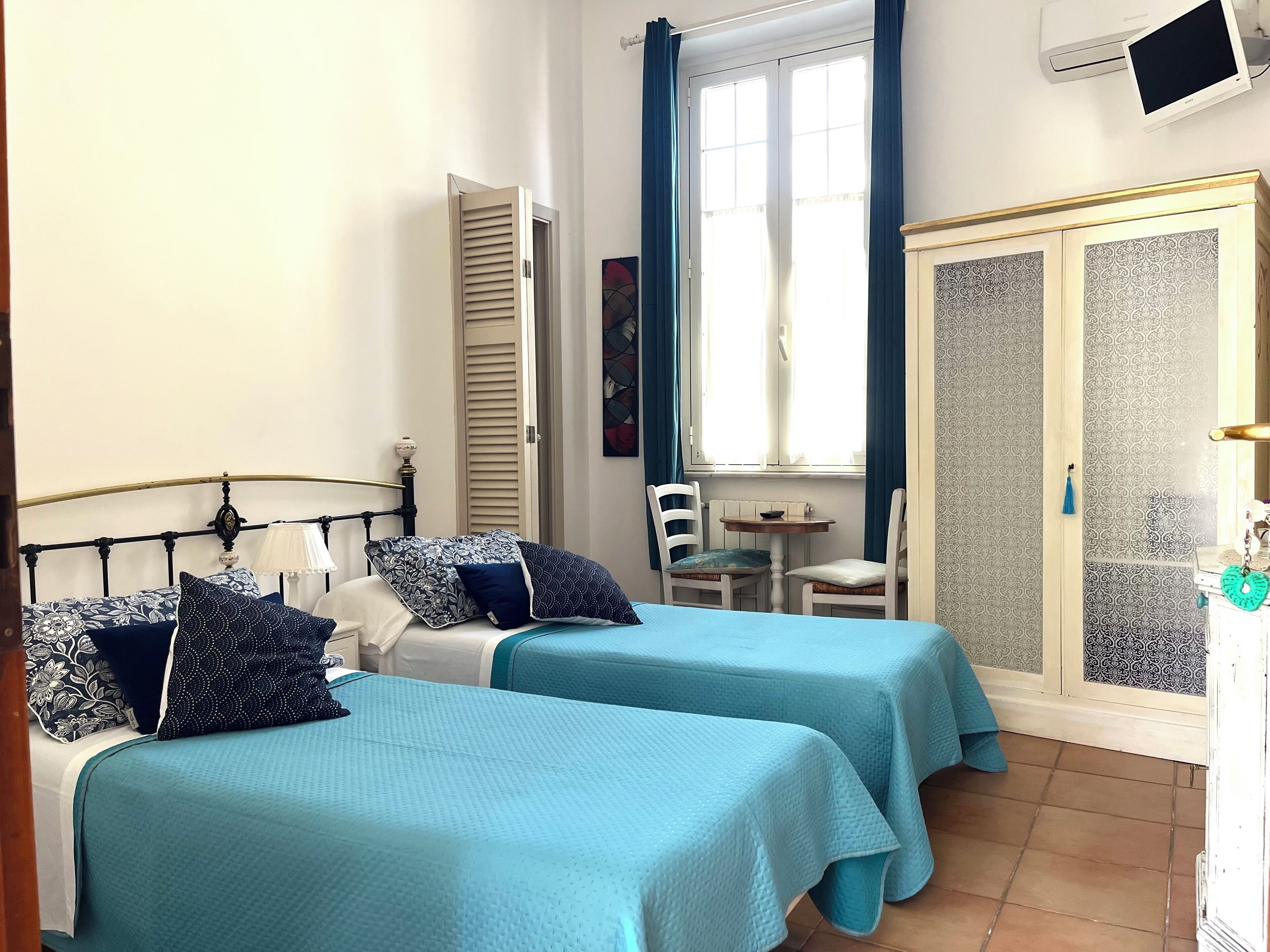 A room with two beds, a small table, and a wardrobe.
