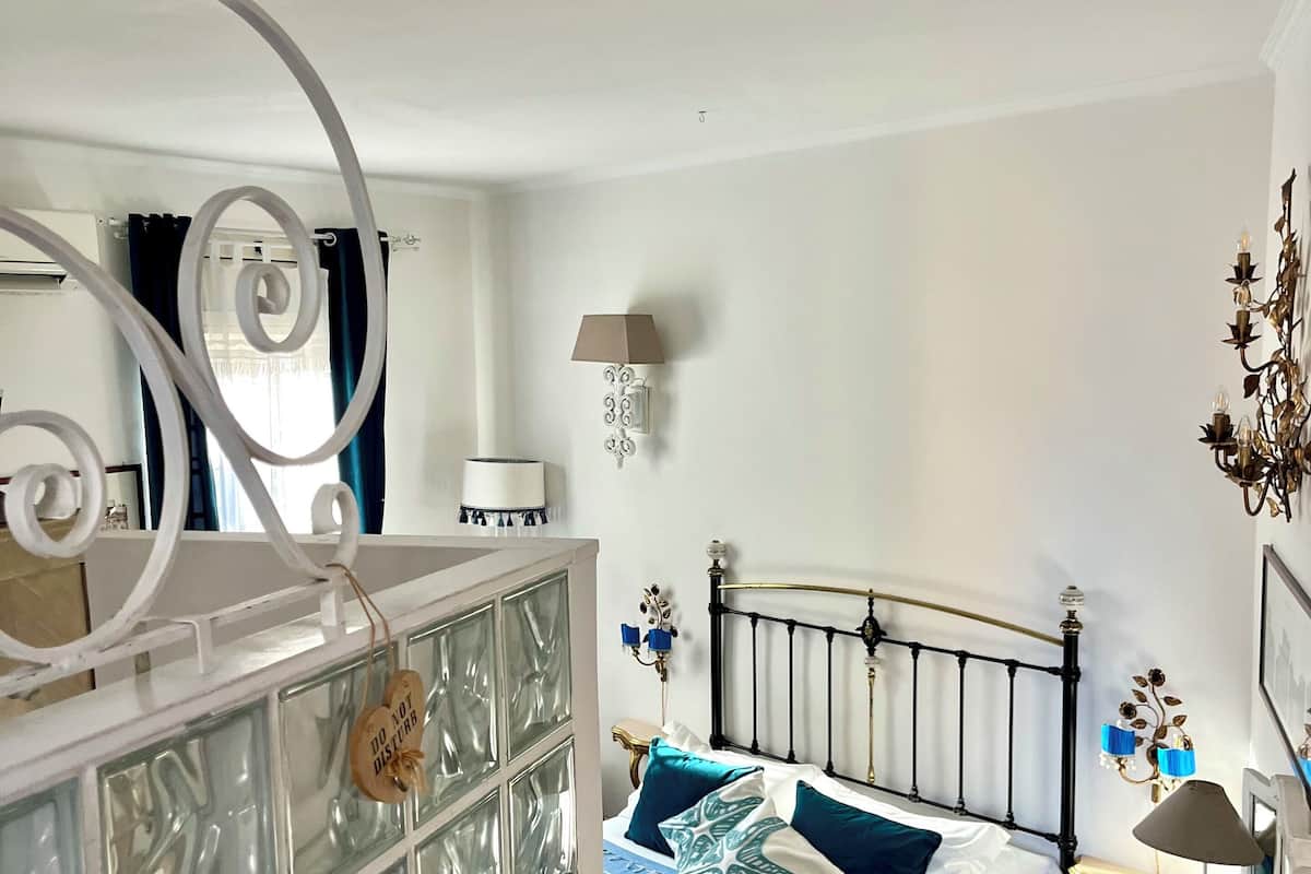 A bedroom with a bed, a nightstand, a dresser, and a window with curtains.