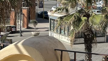 Una calle costera con palmeras, una playa al fondo y un edificio de fachada curva.