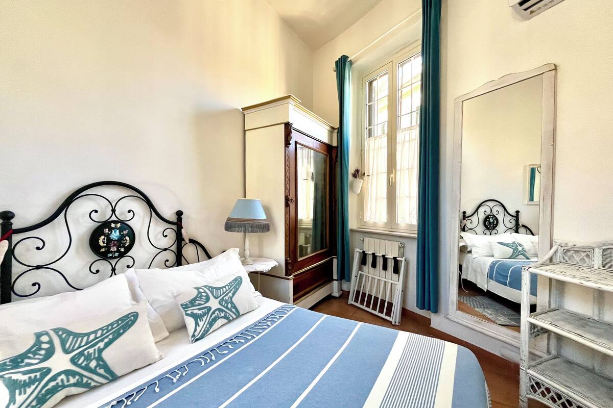 A bedroom with a bed, a nightstand, a dresser, a mirror, and a radiator.