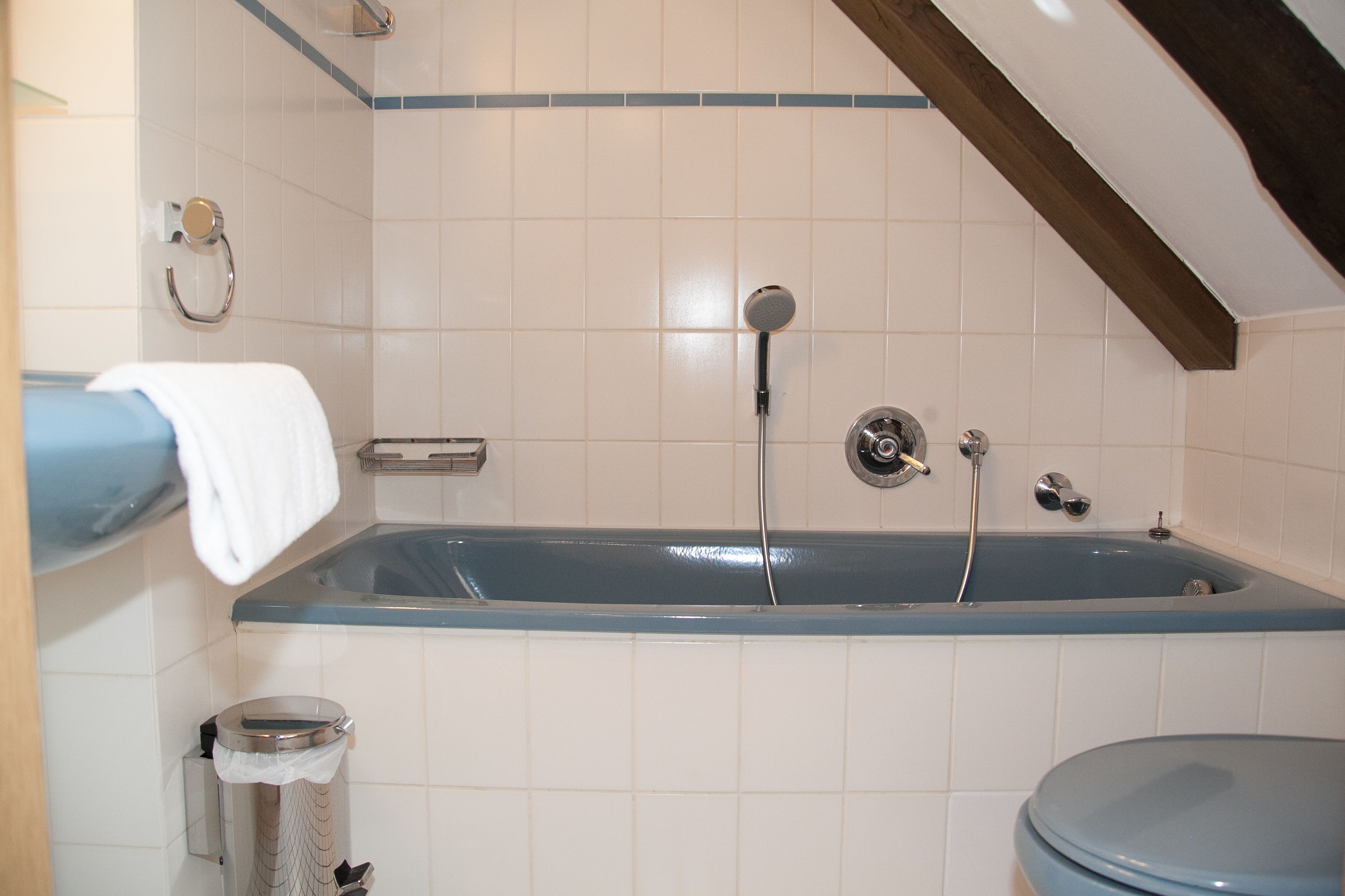 A bathroom with a bathtub, toilet, and a trash bin.