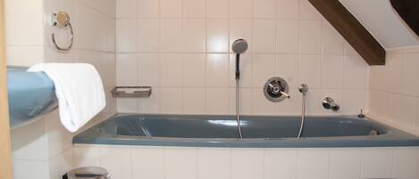 A bathroom with a bathtub, toilet, and a trash bin.
