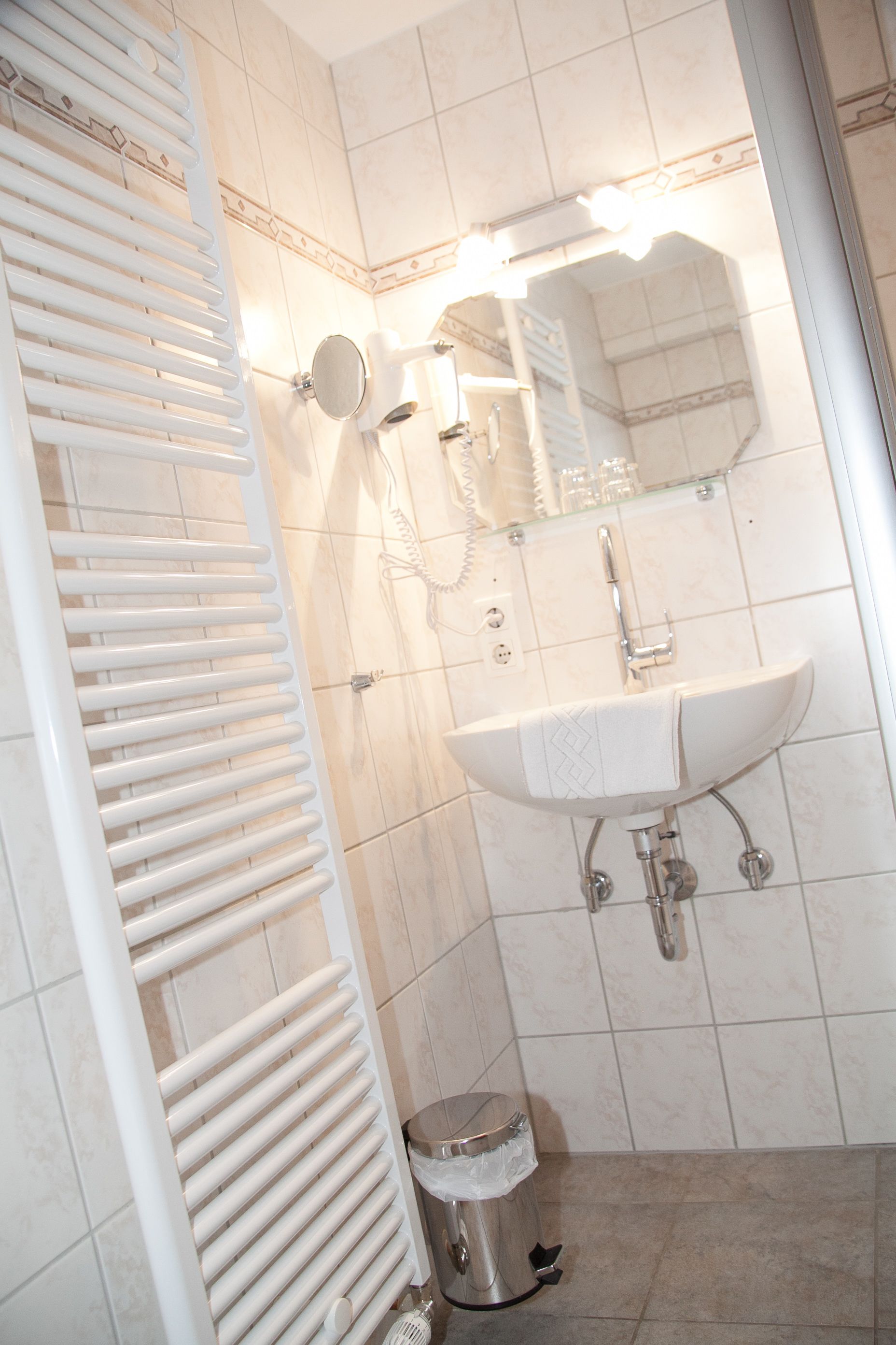 Ein Badezimmer mit weißem Waschbecken, Spiegel und Handtuchhalter.
