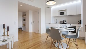 Een moderne keuken met witte kastjes, een magnetron, en een eethoek met een ronde tafel en stoelen.