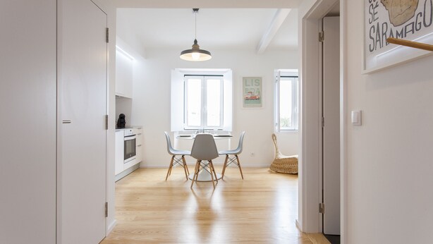 Een moderne keuken met witte kasten, een eettafel met stoelen en een hangende lamp.