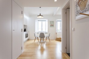 Une cuisine moderne avec des meubles blancs, une table à manger avec des chaises et un luminaire suspendu.