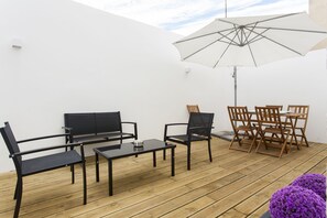 Relax in a serene outdoor space with a wooden deck, metal table, and comfortable seating.