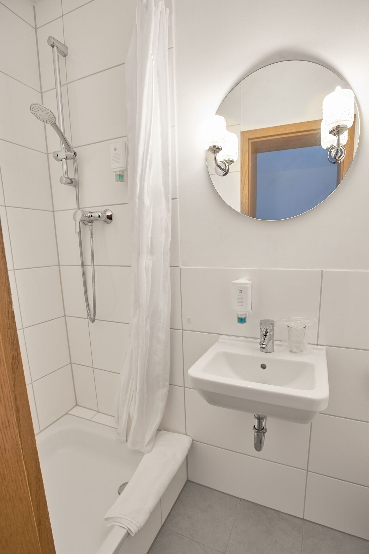 Une salle de bain avec une douche, un lavabo et un miroir.