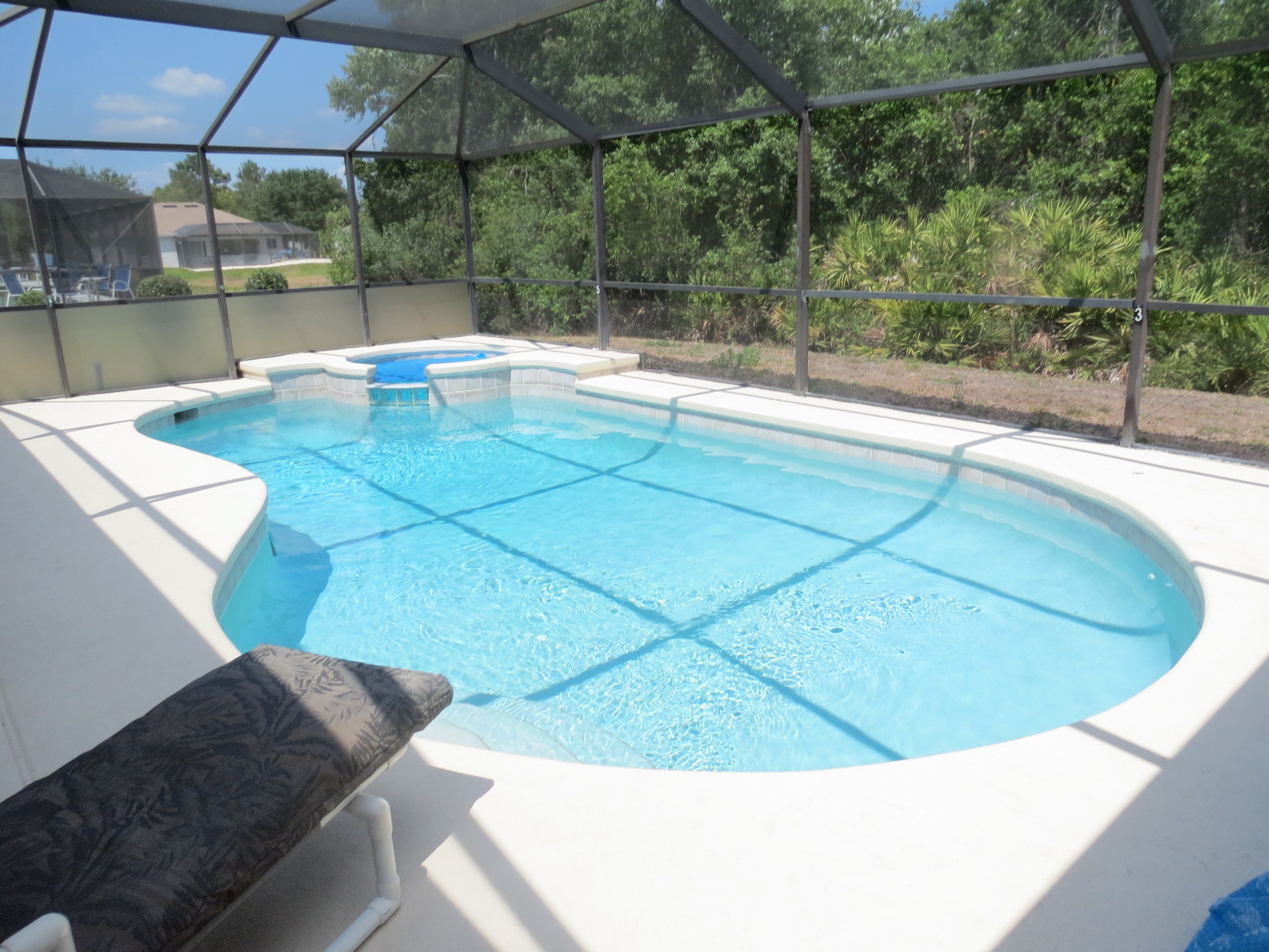 Una piscina con una estructura de sombra, rodeada de vegetación.