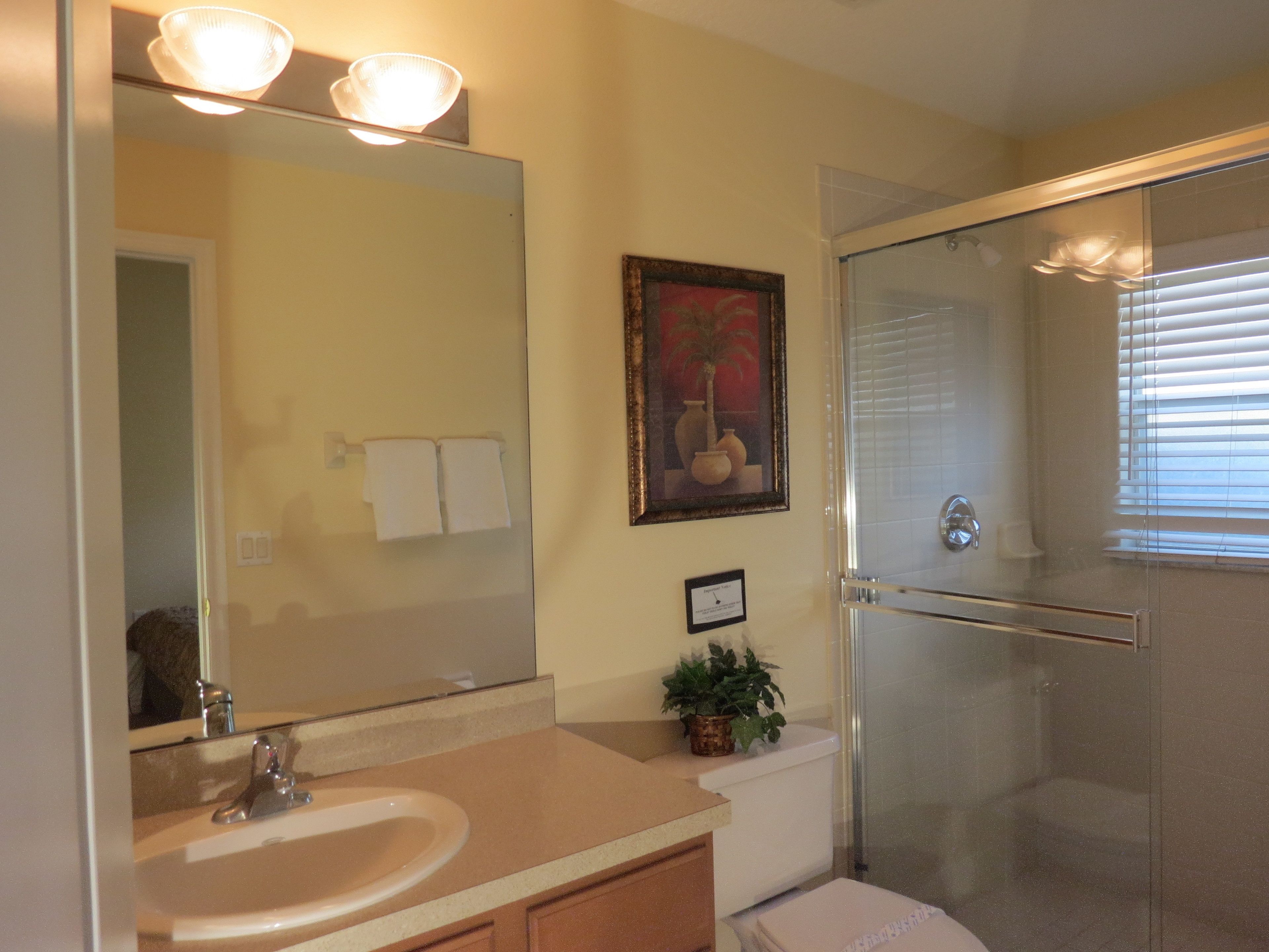 Une salle de bain équipée d’un lavabo, d’un miroir, d’œuvres d’art encadrées et d’une douche à parois de verre.