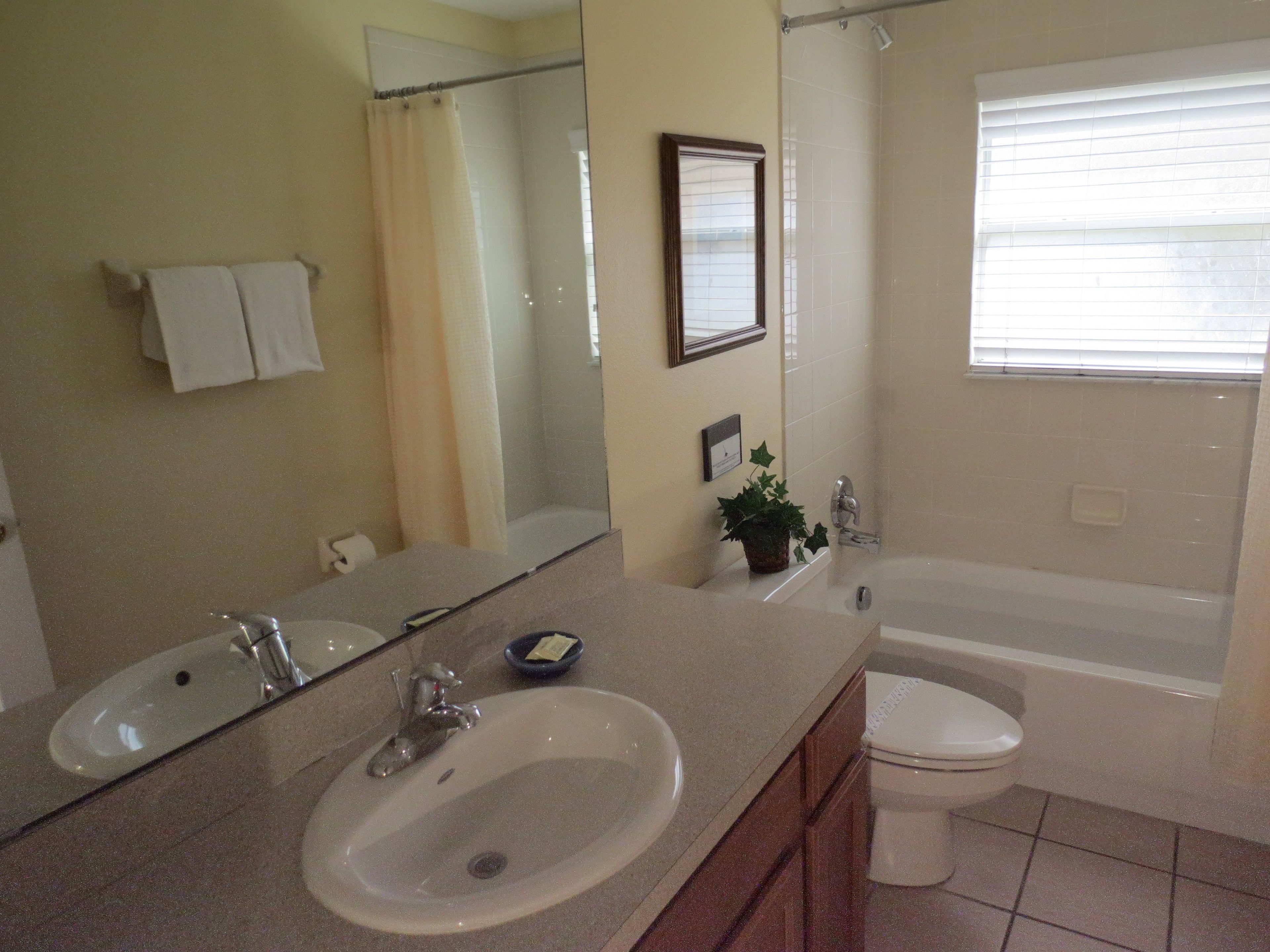 A bathroom with a sink, mirror, toilet, and bathtub.