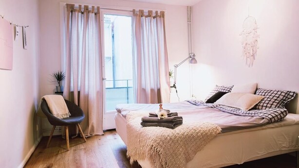 A bedroom with a bed, a chair, a lamp, and a window with curtains.