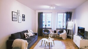 A modern living room with a dark grey sofa, a white coffee table, and a TV on a white cabinet.
