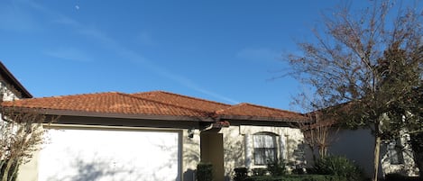 A residential house with a red-tiled roof, a garage, and a well-maintained lawn.