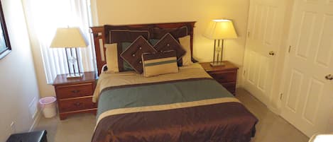 Un dormitorio ordenado con cama, mesitas de noche, lámpara y armario.