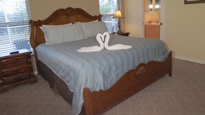 A neatly made bed with a blue bedspread and two white swan-shaped pillows. - Westridge Area Pool Home (Davenport)