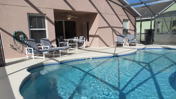 A swimming pool with lounge chairs and a covered patio area. - Westridge Area Pool Home (Davenport)