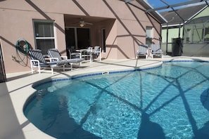 Une piscine avec des chaises longues et un espace patio couvert.