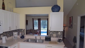 A kitchen with white cabinets, a coffee maker, a toaster, and a sink. - Westridge Area Pool Home (Davenport)