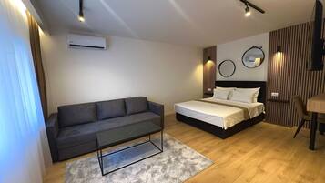 A modern bedroom with a bed, a sofa, a coffee table, and a desk.