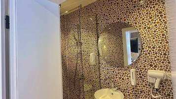 Une salle de bain avec un mur à motifs, un meuble-lavabo en bois, un évier, un miroir et un espace douche.