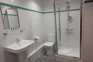 Un baño moderno con ducha envuelta en vidrio, un lavabo blanco y un inodoro.