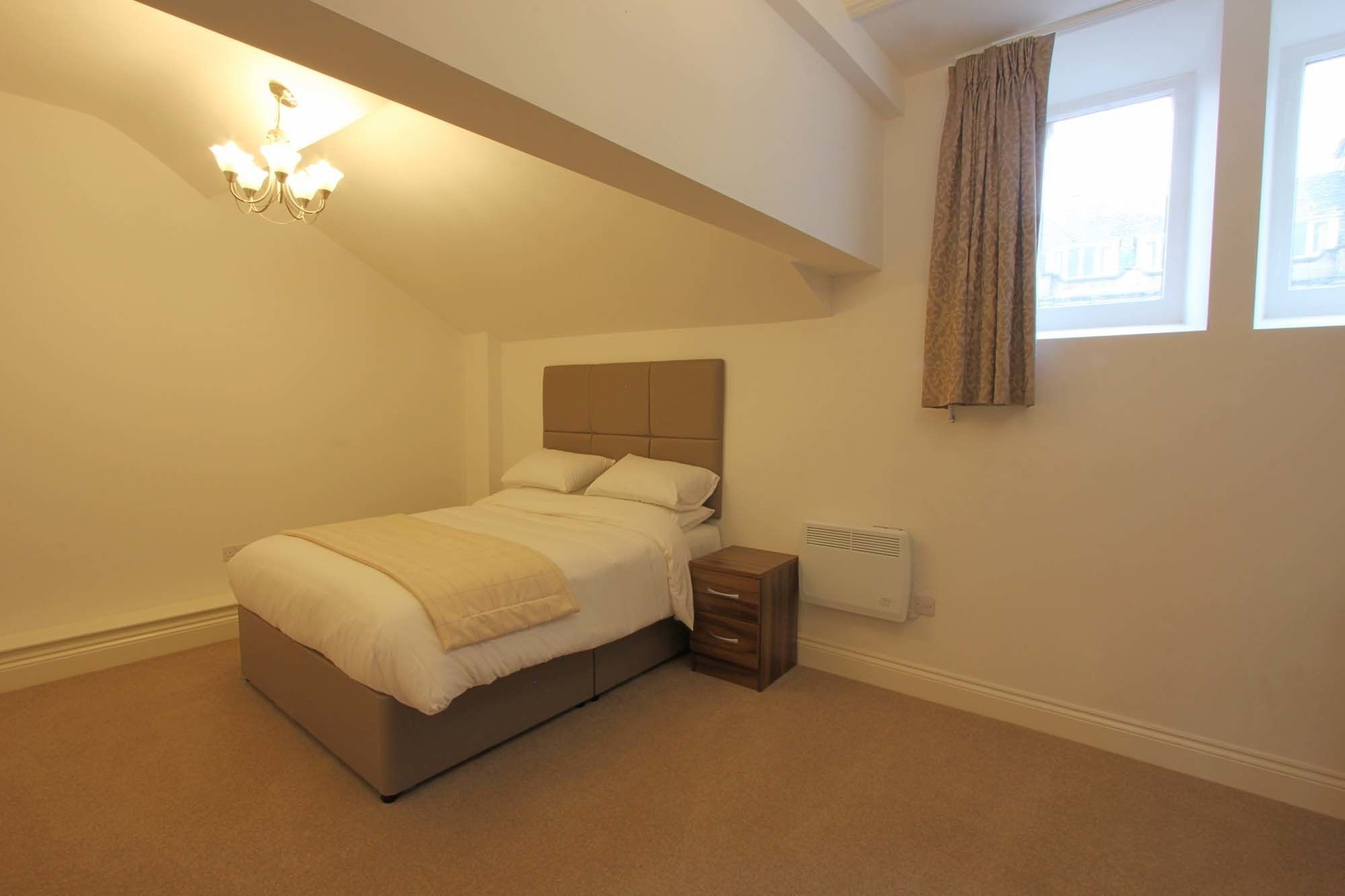 A bedroom with a bed, bedside table, and a radiator.