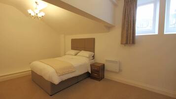 A bedroom with a bed, bedside table, and a radiator.
