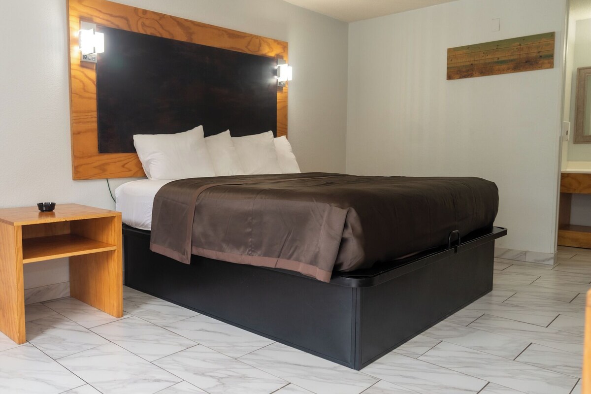 A modern bedroom with a bed, bedside table, and a headboard with integrated lighting.