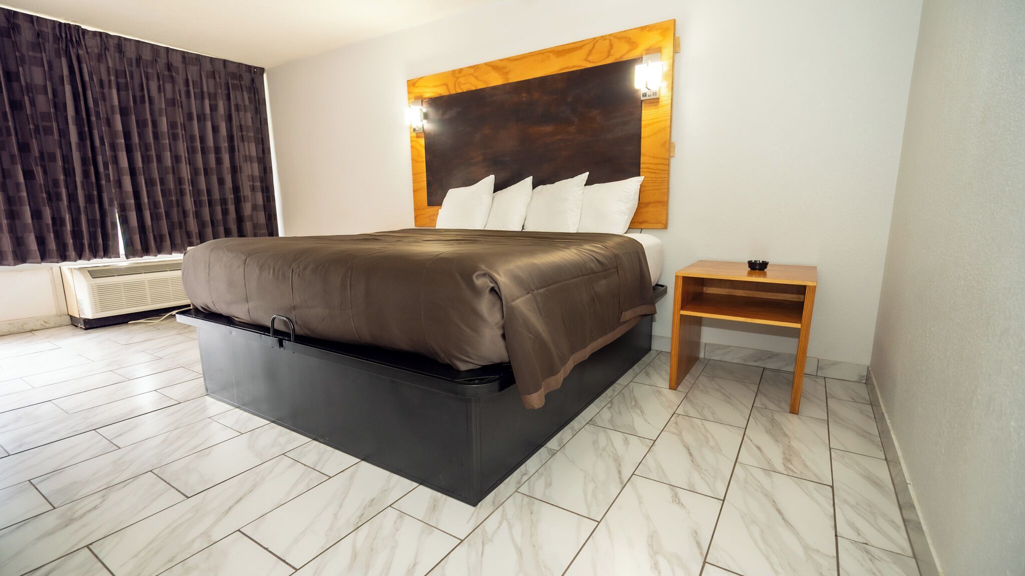 Un dormitorio moderno con cama, mesita de noche y una lámpara de pared.
