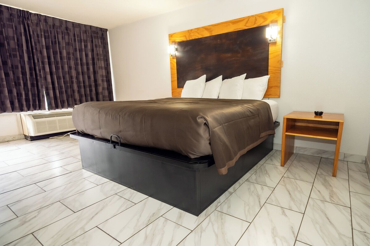 A modern bedroom with a bed, bedside table, and a wall-mounted light fixture.