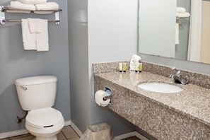 Un baño con inodoro, lavamanos y perchero para toallas.