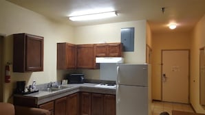 Una cocina compacta con armarios de madera, un microondas, una estufa y un refrigerador.
