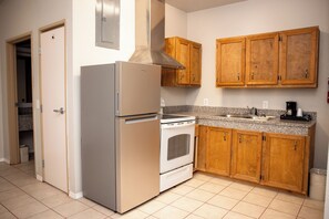 A kitchen with a refrigerator, oven, and wooden cabinets. - Days Inn by Wyndham Plainview Texas (Plainview)
