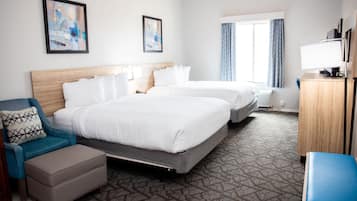 A hotel room with two beds, a desk, a chair, and a window with curtains.