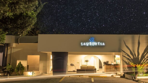 Un hotel llamado "Laurentina" con una fachada moderna, una entrada visible y un cielo nocturno estrellado.