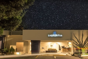Ein Hotel namens "Laurentina" mit moderner Fassade, einem gut sichtbaren Eingang und einem sternenübersäten Nachthimmel.