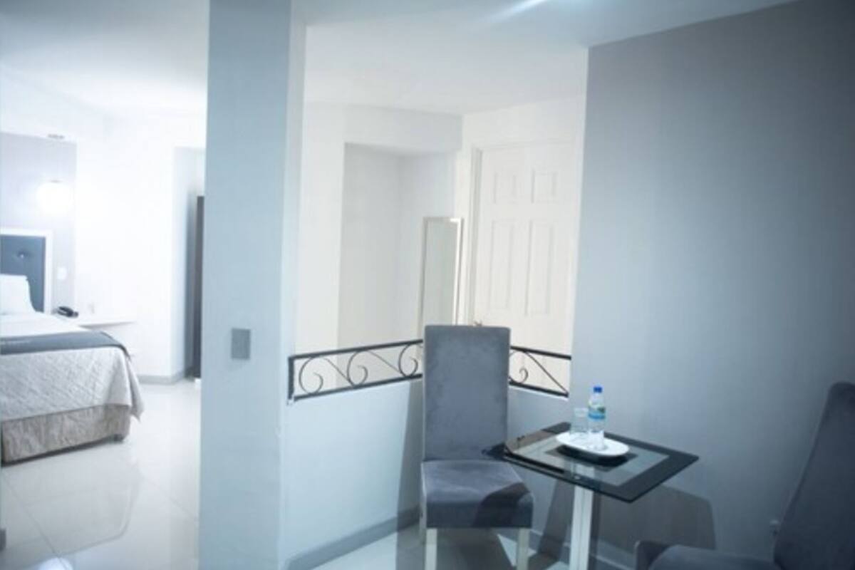 A hotel room with a bed, a small table with a chair, and a water bottle on the table.