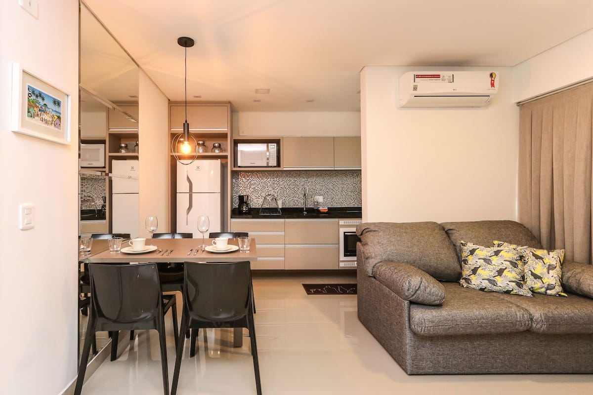 Cozinha moderna com micro-ondas, fogão e área de jantar com cadeiras e mesa.