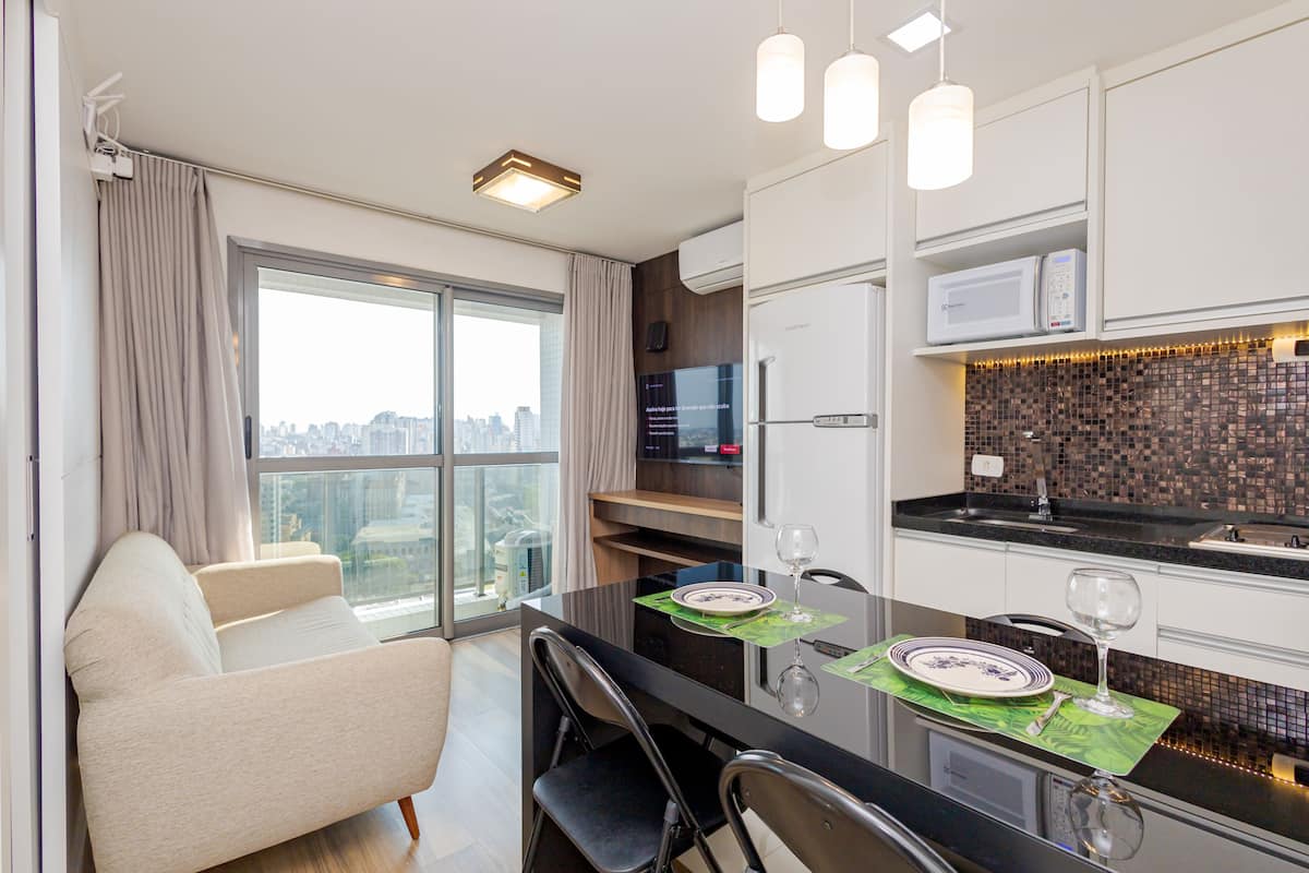 Uma cozinha moderna com área de jantar, um sofá e vista para a cidade.
