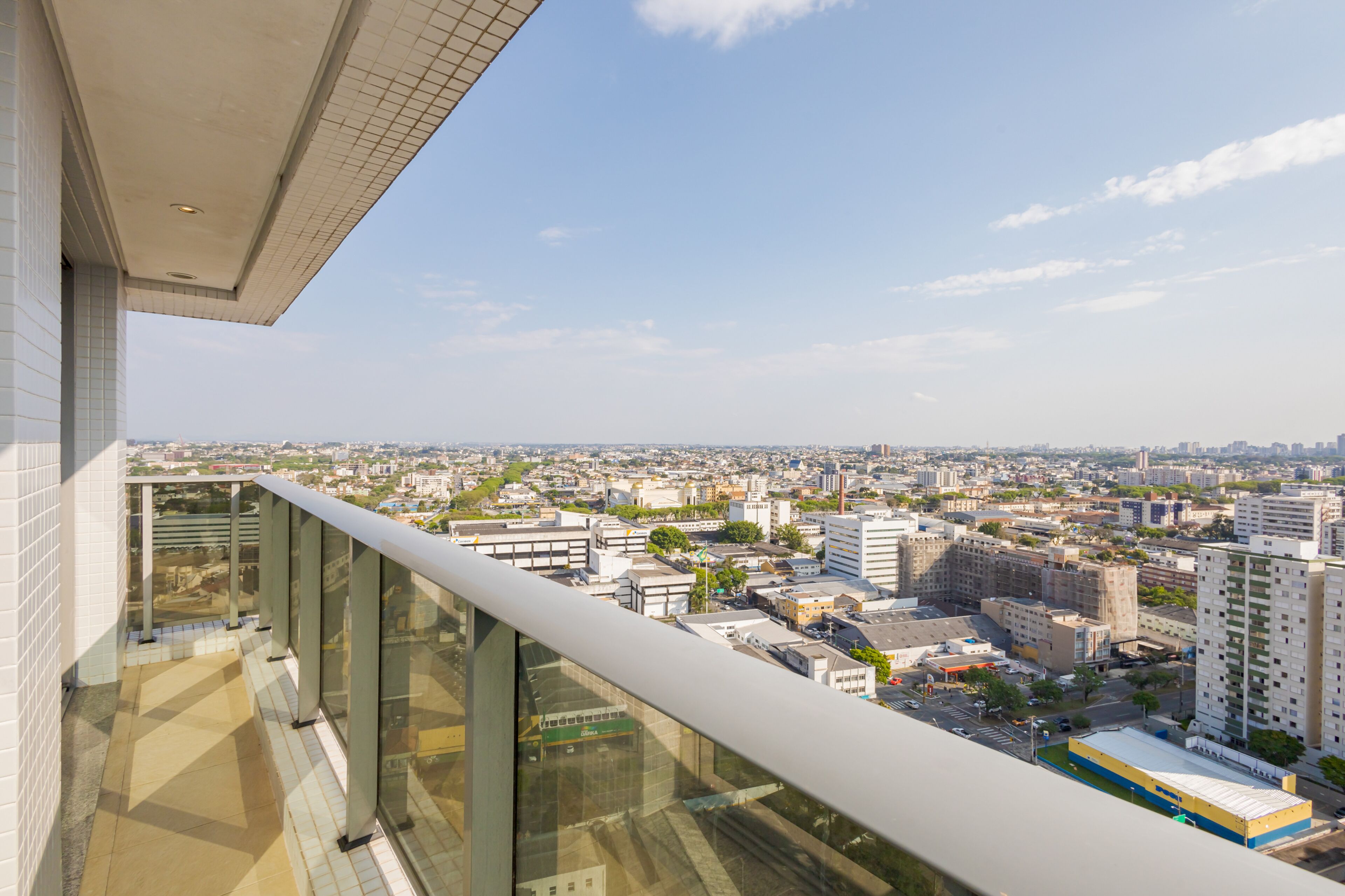 A high-rise building with a glass balcony overlooking a cityscape.