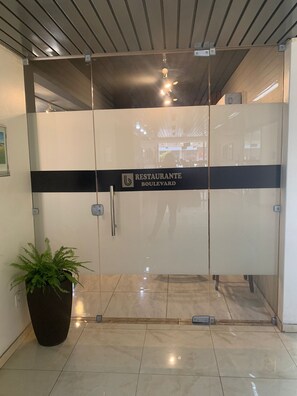 Uma entrada moderna com porta de vidro e uma placa com a inscrição RESTAURANTE BOULEVARD.