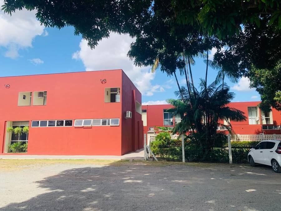 A red building with multiple windows and a parking area.