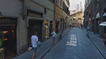 A narrow street with shops on both sides and a Via delle Delle Arti sign painted on the road.