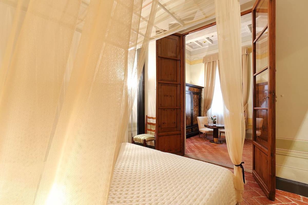 A bedroom with a bed, a wooden door, and a chair.
