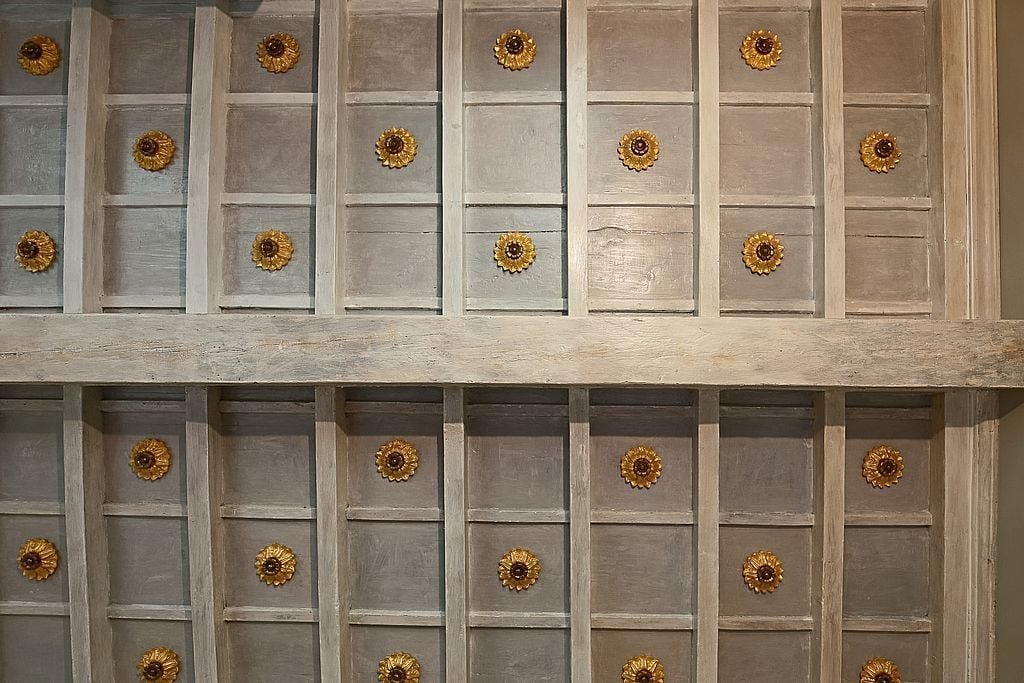 Un mur orné d’un motif en réseau de panneaux, chacun présentant un élément décoratif central rappelant une fleur.