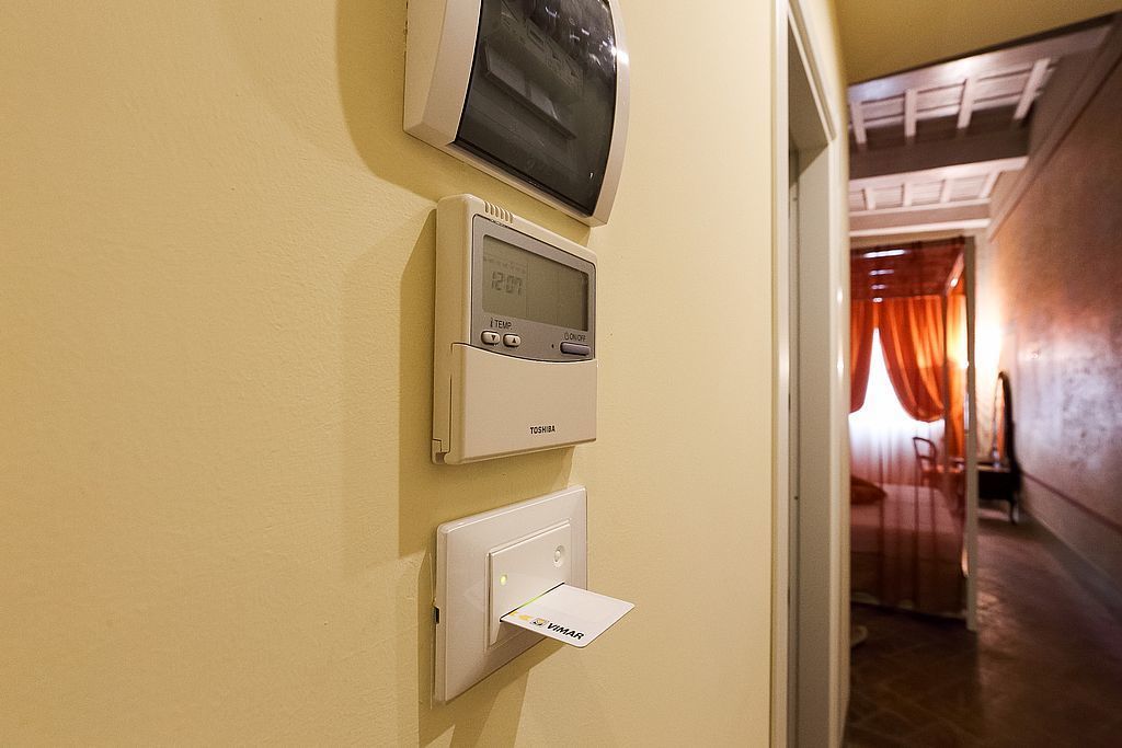 Un thermostat fixé au mur et un lecteur de carte, indiquant le contrôle de la température de la pièce et l’accès à un système basé sur l’utilisation de cartes.