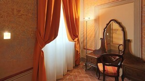 Quarto com um espelho grande, uma cadeira de madeira e uma janela com cortinas laranja.