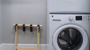 A laundry area with two stacked washing machines and a drying rack.